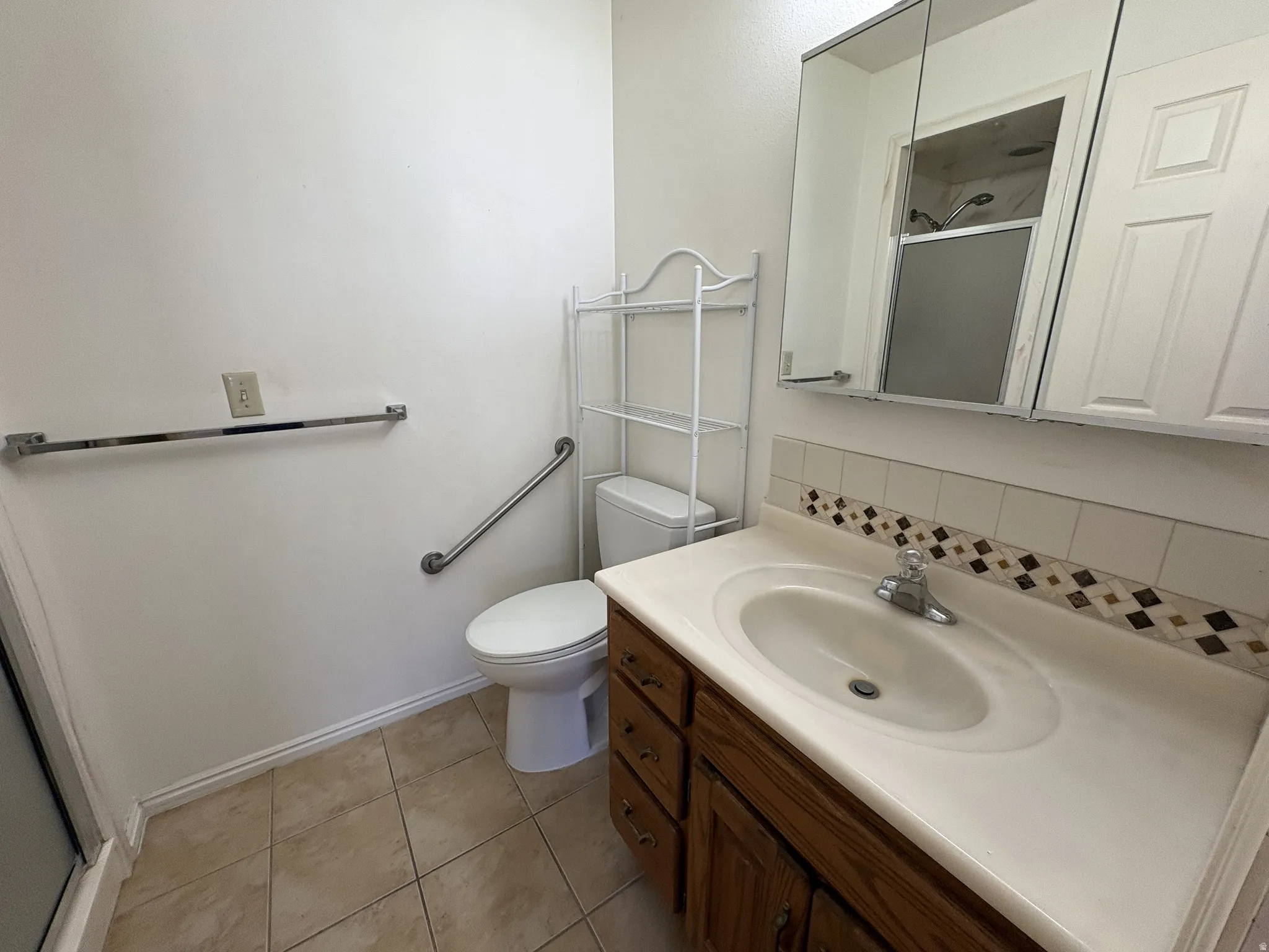 Bathroom featuring a wood-finish vanity with an integrated sink and a neutral countertop