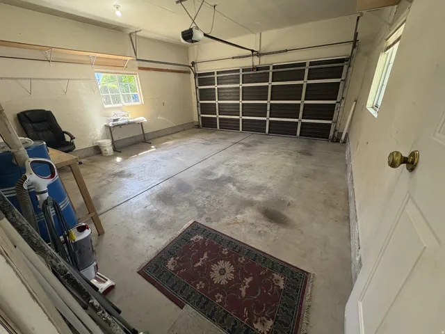 Spacious garage with an overhead sectional door, concrete flooring, and a single window