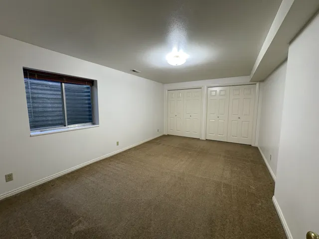 Spacious room featuring neutral carpeting and white walls