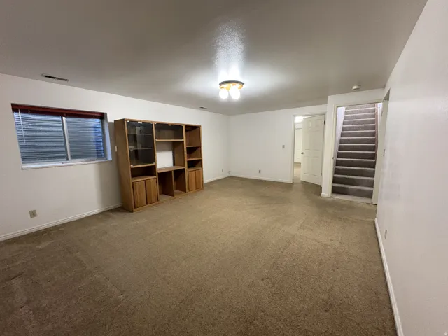 Carpeted room with white walls and a built-in wood-finish storage unit