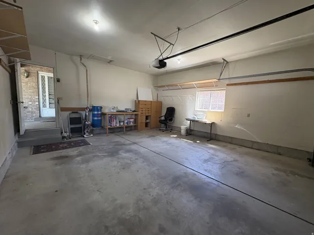 Spacious 2 car garage featuring a concrete floor, overhead lighting, an interior access door, a transom window, and built-in shelving