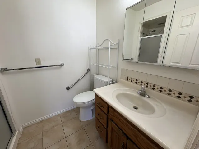 Bathroom featuring a wood-finish vanity with an integrated sink and a neutral countertop