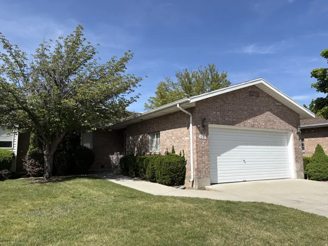 Brick exterior featuring a white garage door, concrete driveway, and front lawn