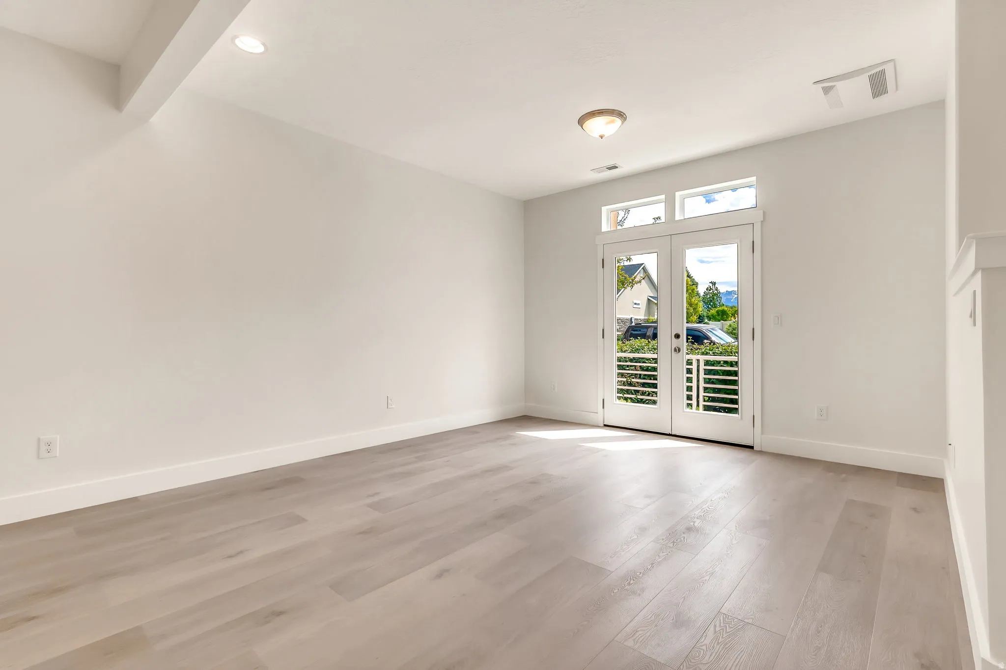Bright room featuring light wood-finish flooring, white walls, and a ceiling light fixture
