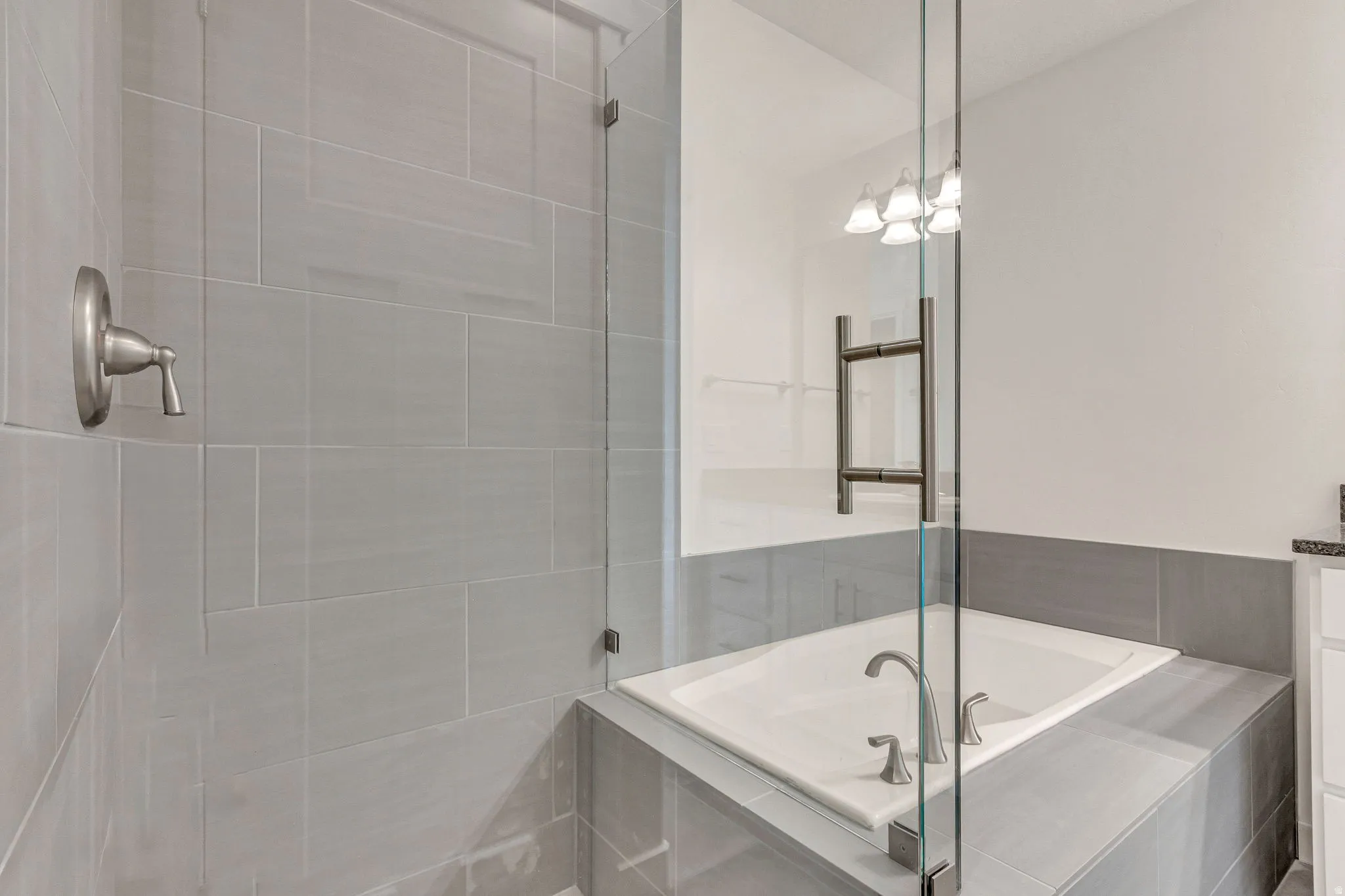 Glass-enclosed shower with light gray tile surround and brushed nickel fixtures