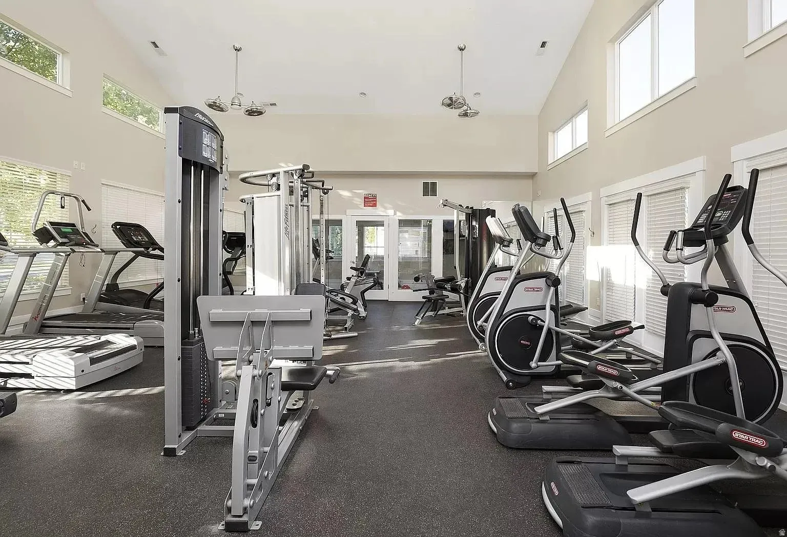 Fitness area featuring various exercise machines, high ceilings, large windows, recessed lighting, and rubberized flooring
