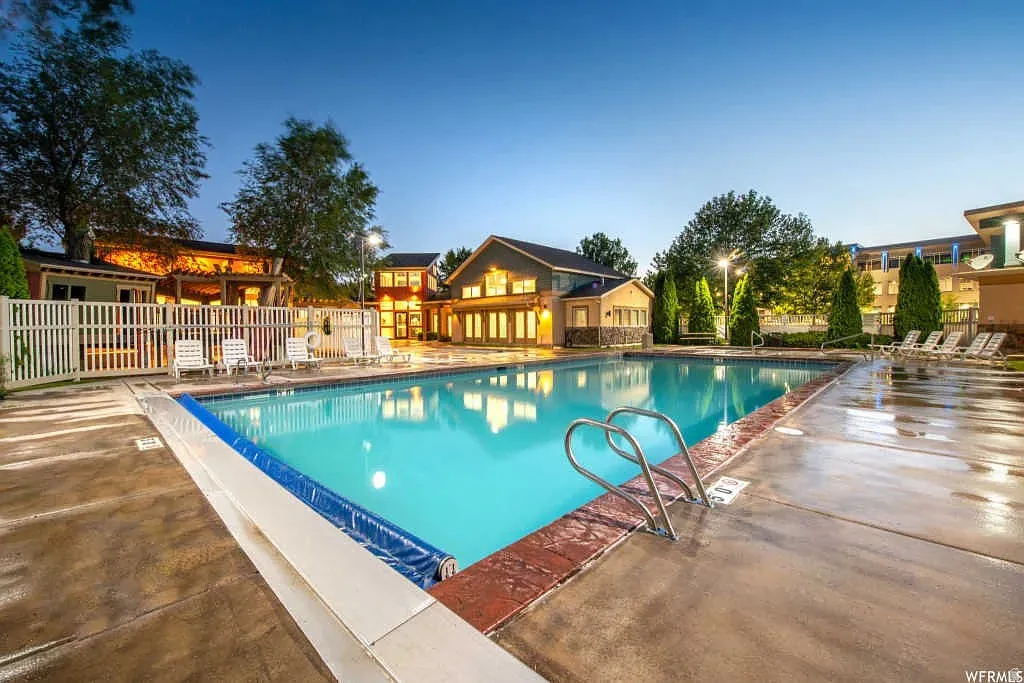 Outdoor swimming pool featuring a ladder, concrete decking, and brick coping