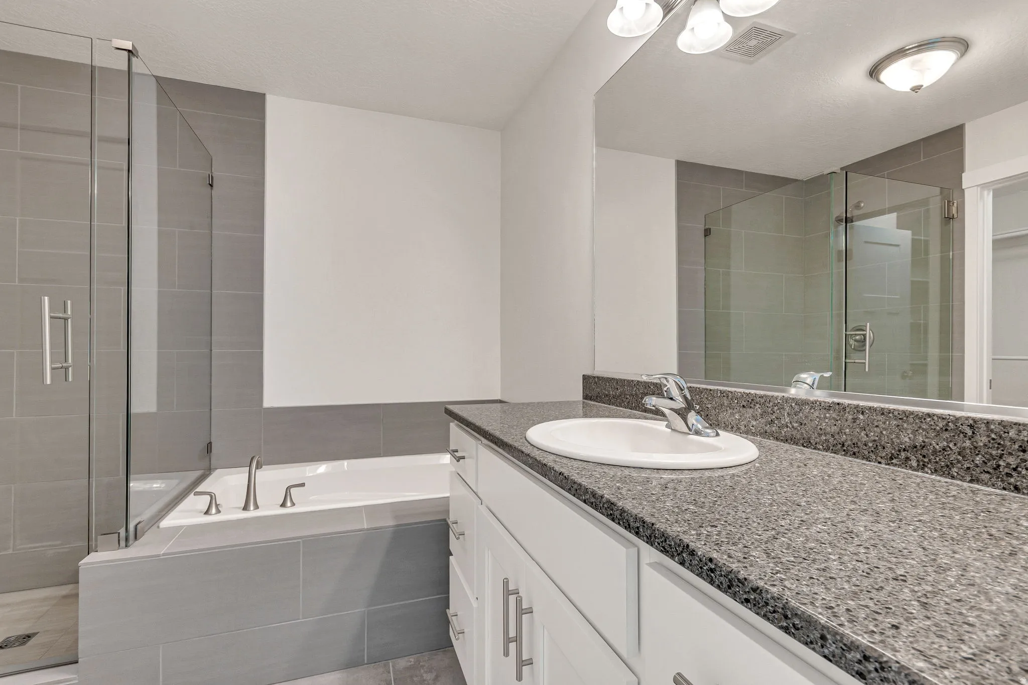 Bathroom featuring a vanity with a speckled countertop, undermount sink, and chrome faucet
