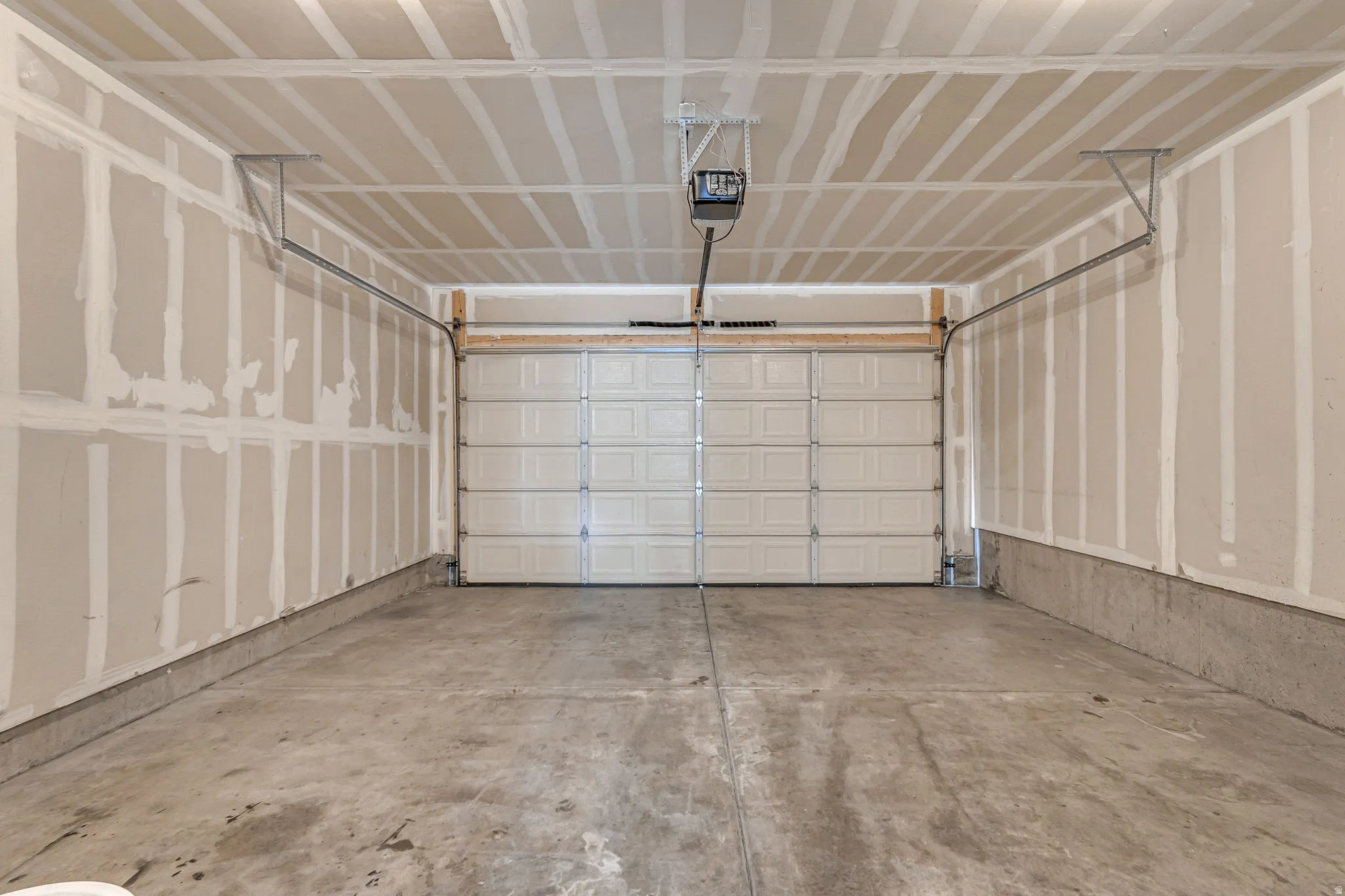 Spacious two-car garage featuring a sectional overhead door and concrete flooring