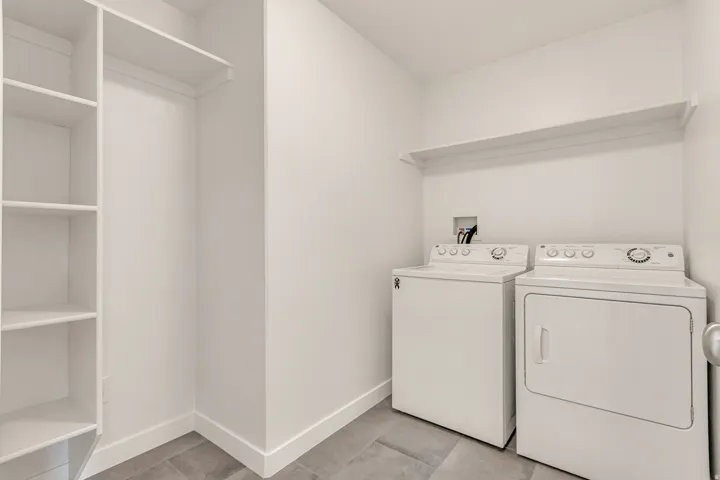 Laundry area featuring a top-load washing machine, front-load dryer, and a wall-mounted shelf