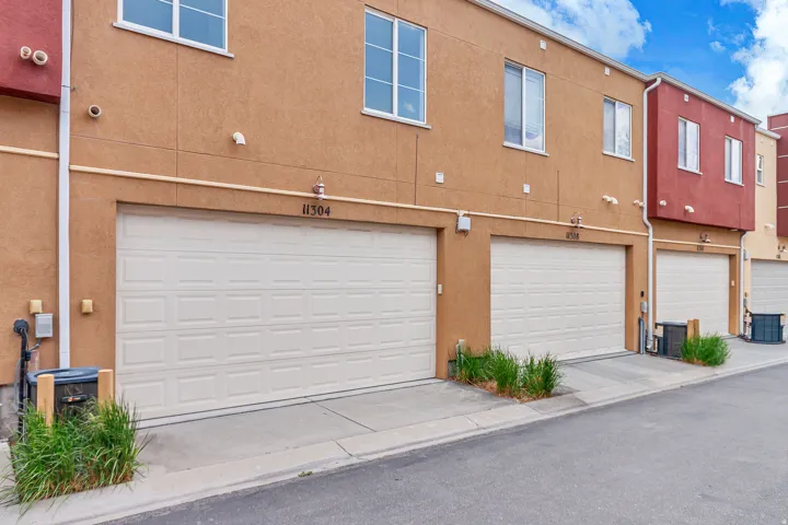 Multi-story exterior featuring stucco siding in warm earth tones with contrasting red accents