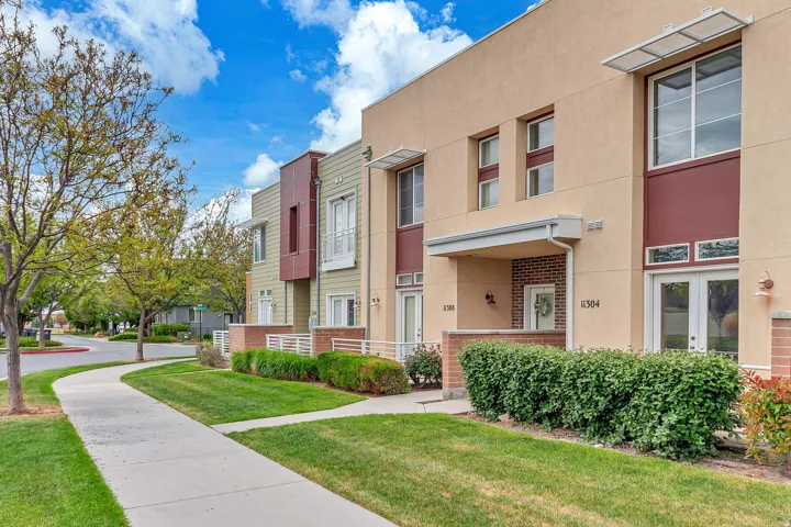 Contemporary townhouse exterior with a cream stucco finish and brick accents