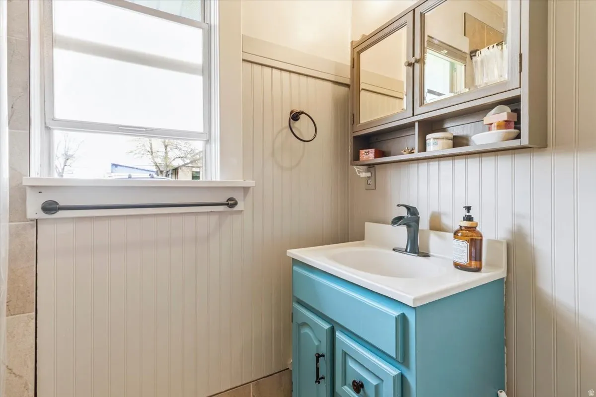 Bathroom featuring a single window, beadboard wall paneling, and a light blue vanity with a white countertop
