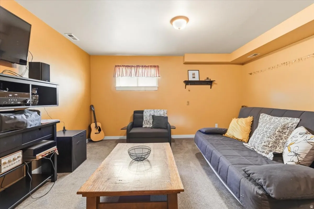 Carpeted room with a ceiling-mounted light fixture, a window with white trim, and a built-in wall shelf