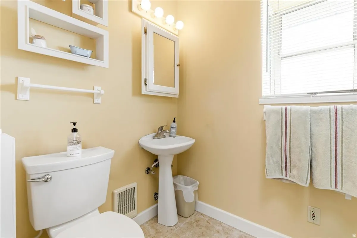 Full bathroom featuring a pedestal sink, wall-mounted medicine cabinet with vanity lighting, and a toilet