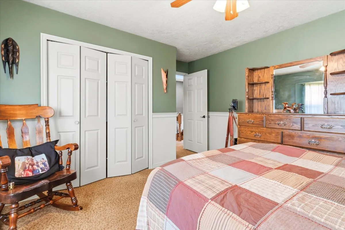 Carpeted bedroom with green wall paint, white wainscoting and double door closets.