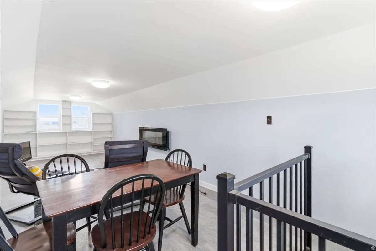 Vaulted ceiling bonus room featuring built-in shelving, two windows, and an electric fireplace