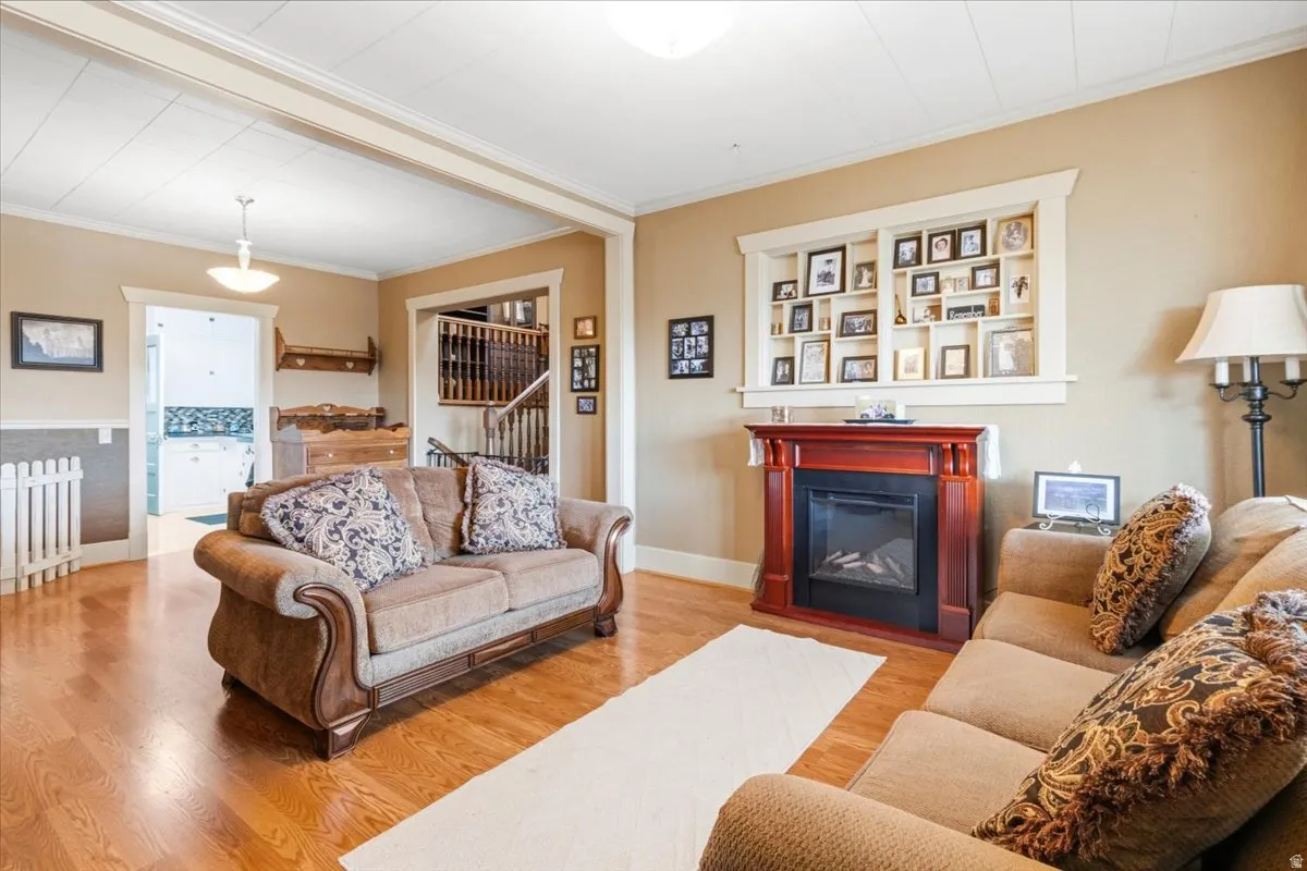 Living area featuring wood-finish flooring, a decorative fireplace with a mantel, built-in shelving, and neutral wall tones