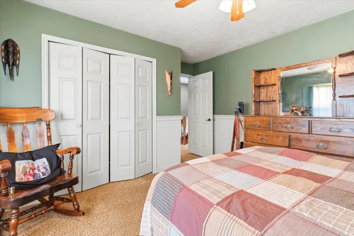 Carpeted bedroom with green wall paint, white wainscoting and double door closets.