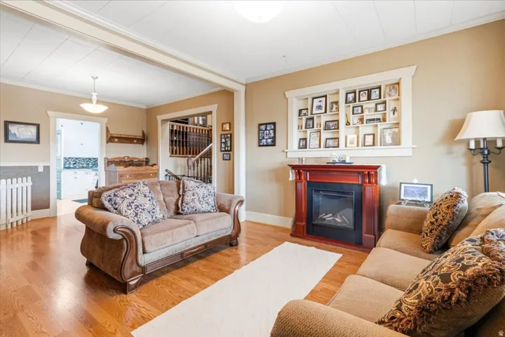 Living area featuring wood-finish flooring, a decorative fireplace with a mantel, built-in shelving, and neutral wall tones