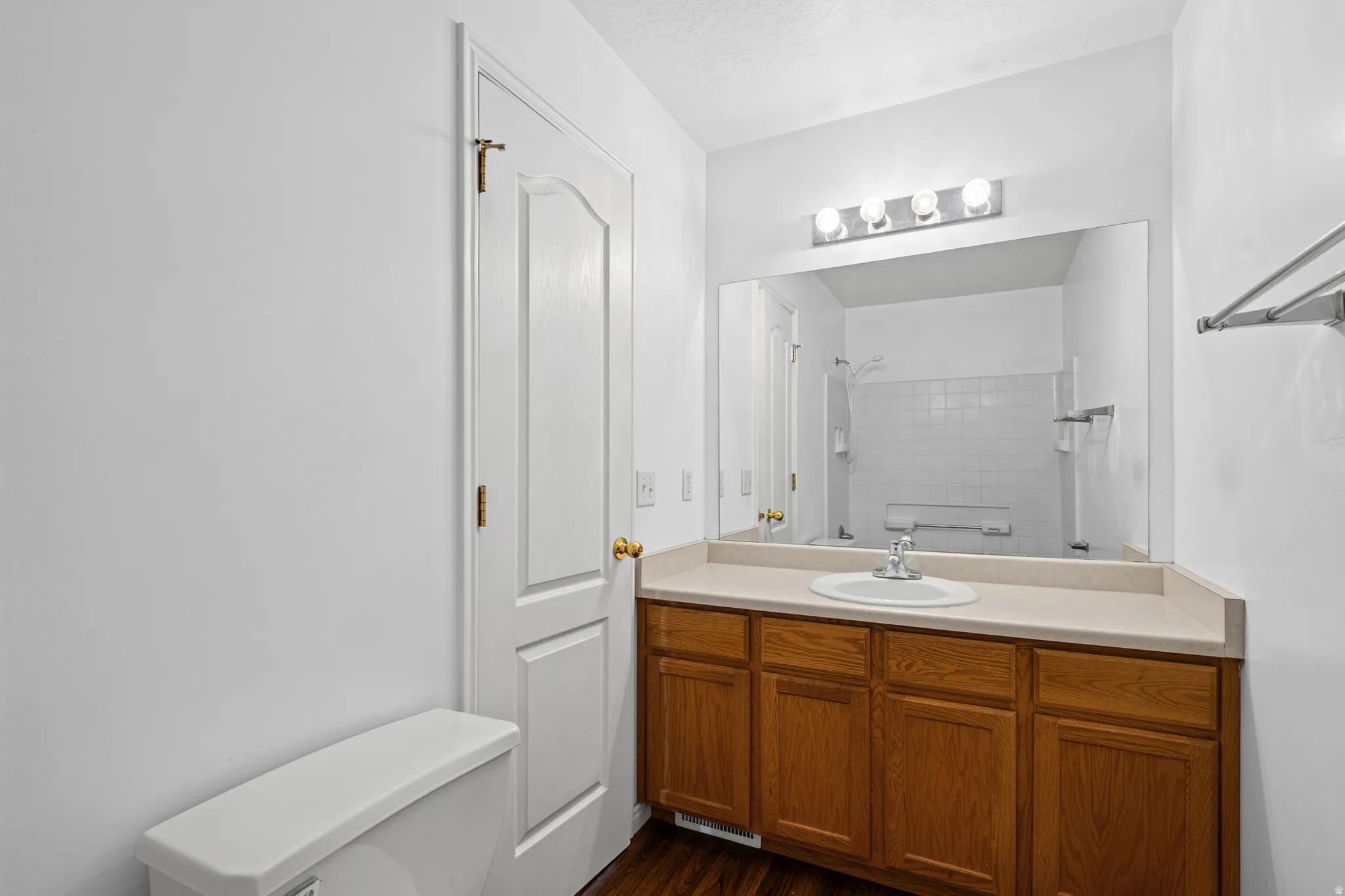 Bathroom featuring a single vanity with wood cabinetry, a neutral countertop, and a large wall-mounted mirror