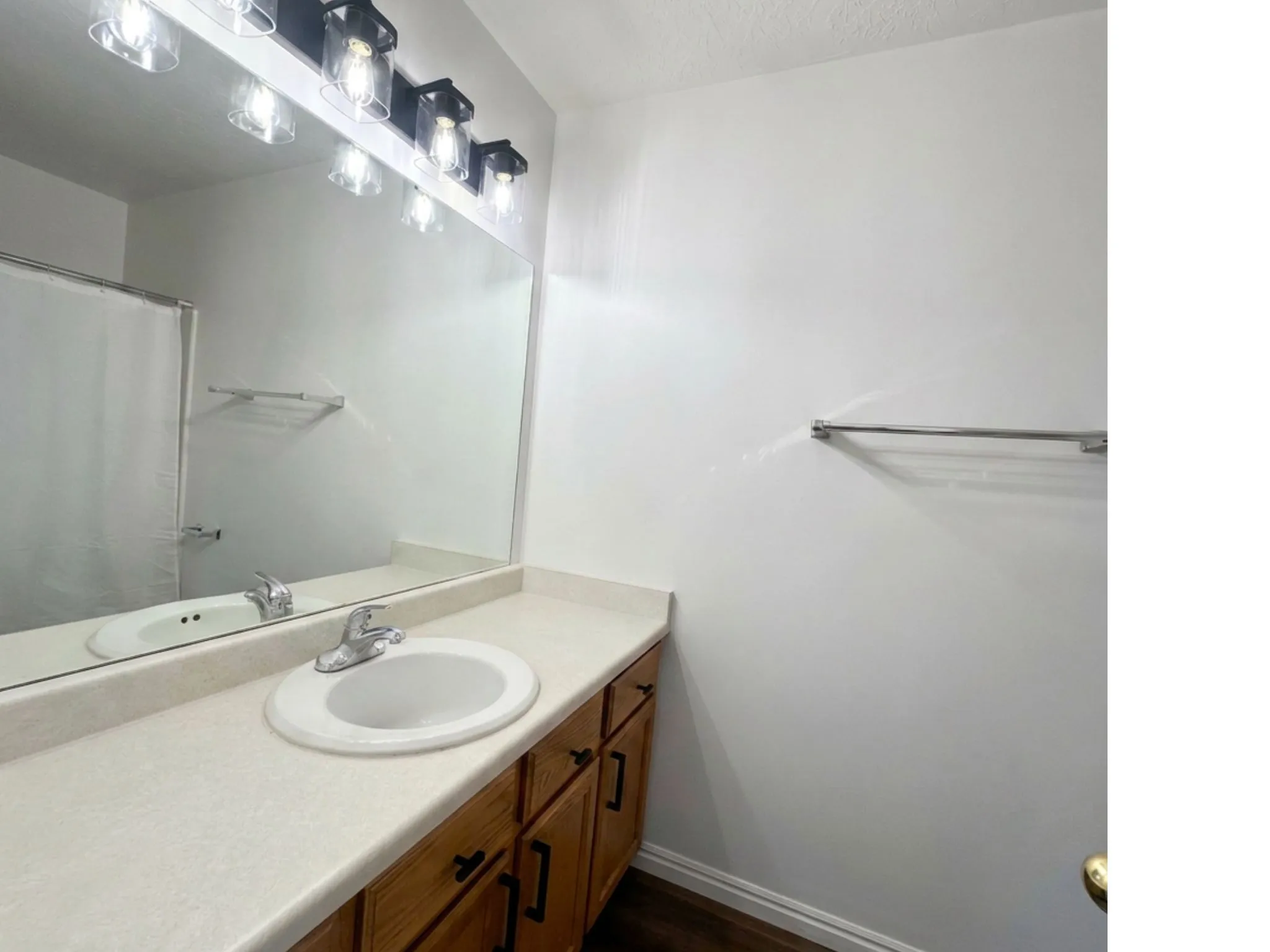 Vanity with an integrated sink, polished chrome faucet, wood-finish cabinetry, and a large wall mirror