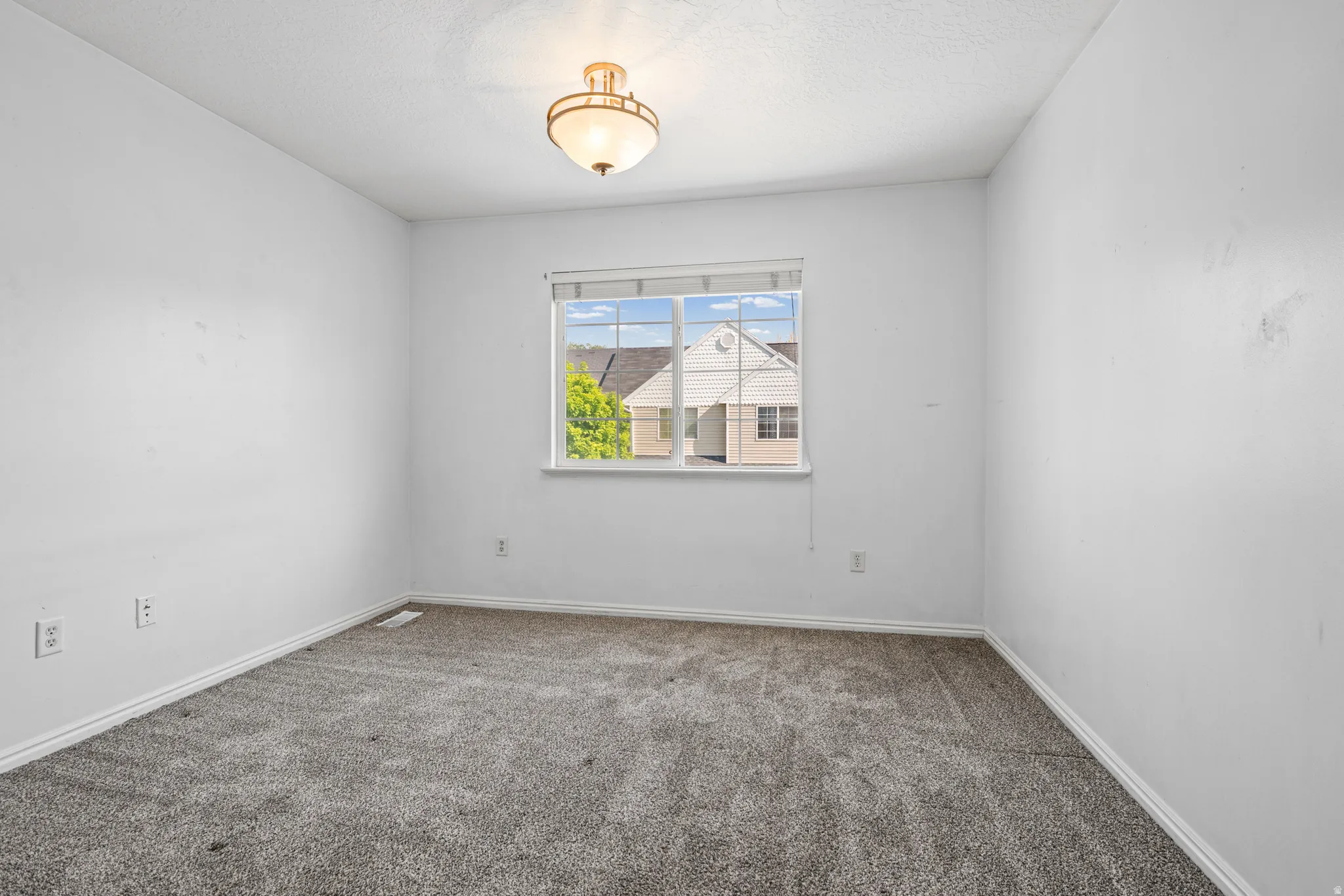 Room featuring a single window with white trim, a semi-flush mount ceiling light fixture, wall-to-wall gray carpet, and white baseboards