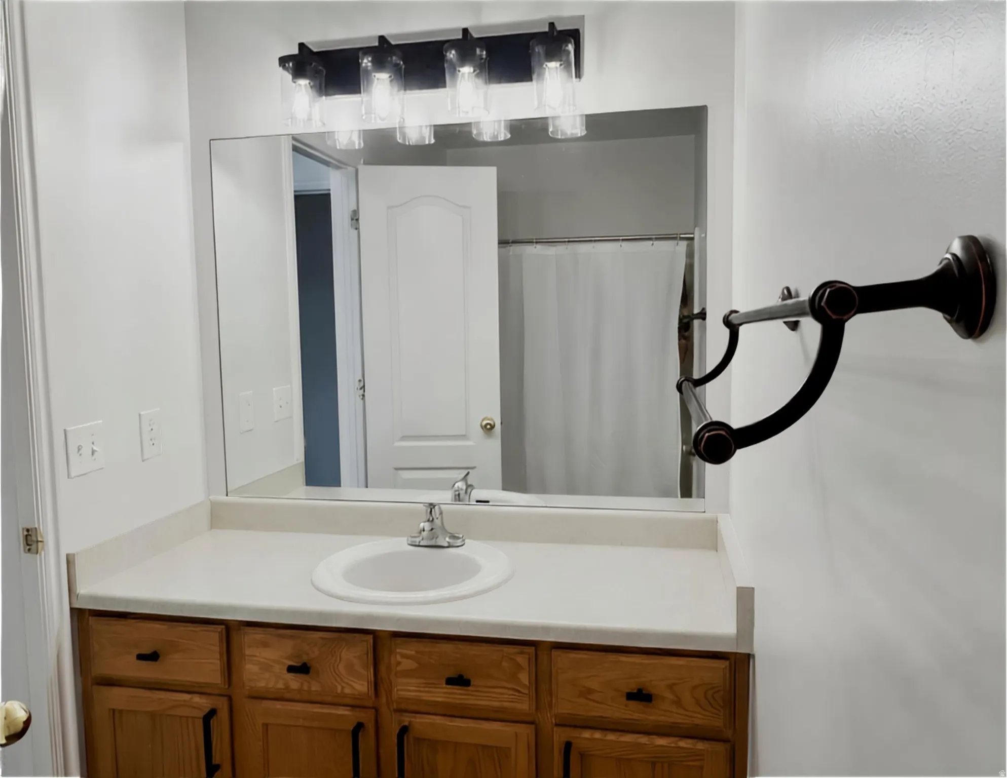 Vanity with wood-finish cabinetry, white countertop, and integrated sink