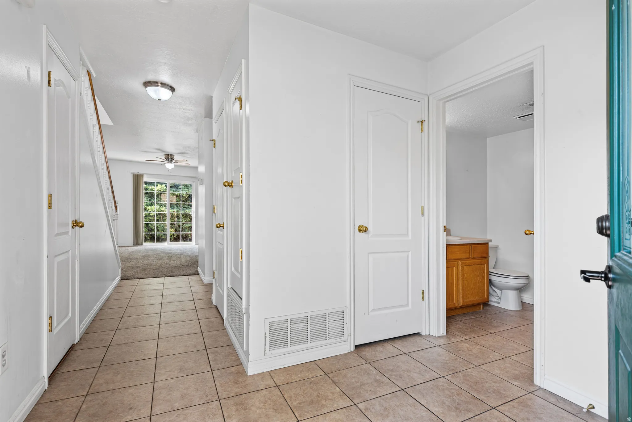 Entryway featuring ceramic tile flooring, a half bathroom with a wood vanity, and a staircase