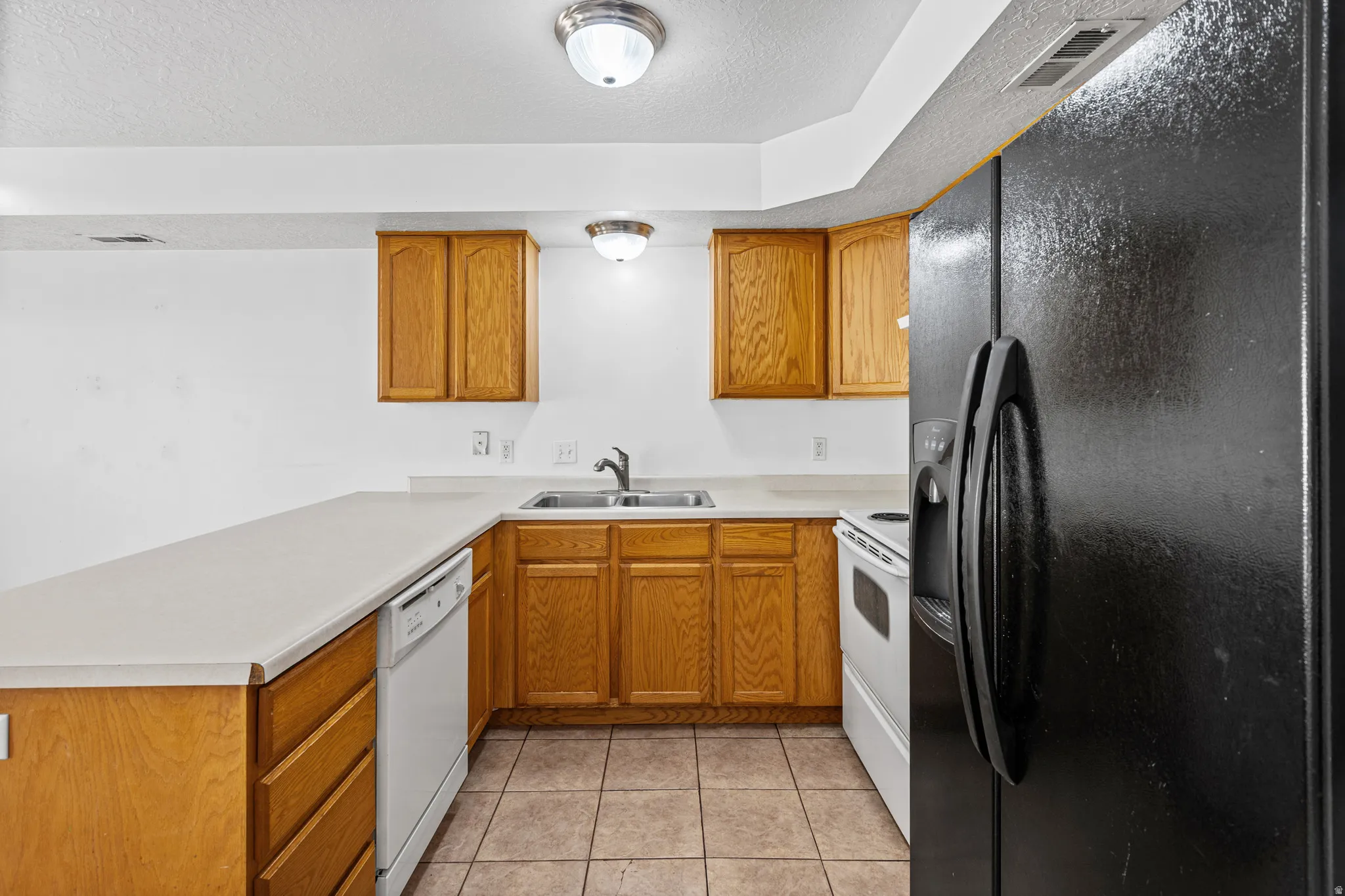 U-shaped kitchen featuring wood cabinetry, light-toned countertops, and tile flooring