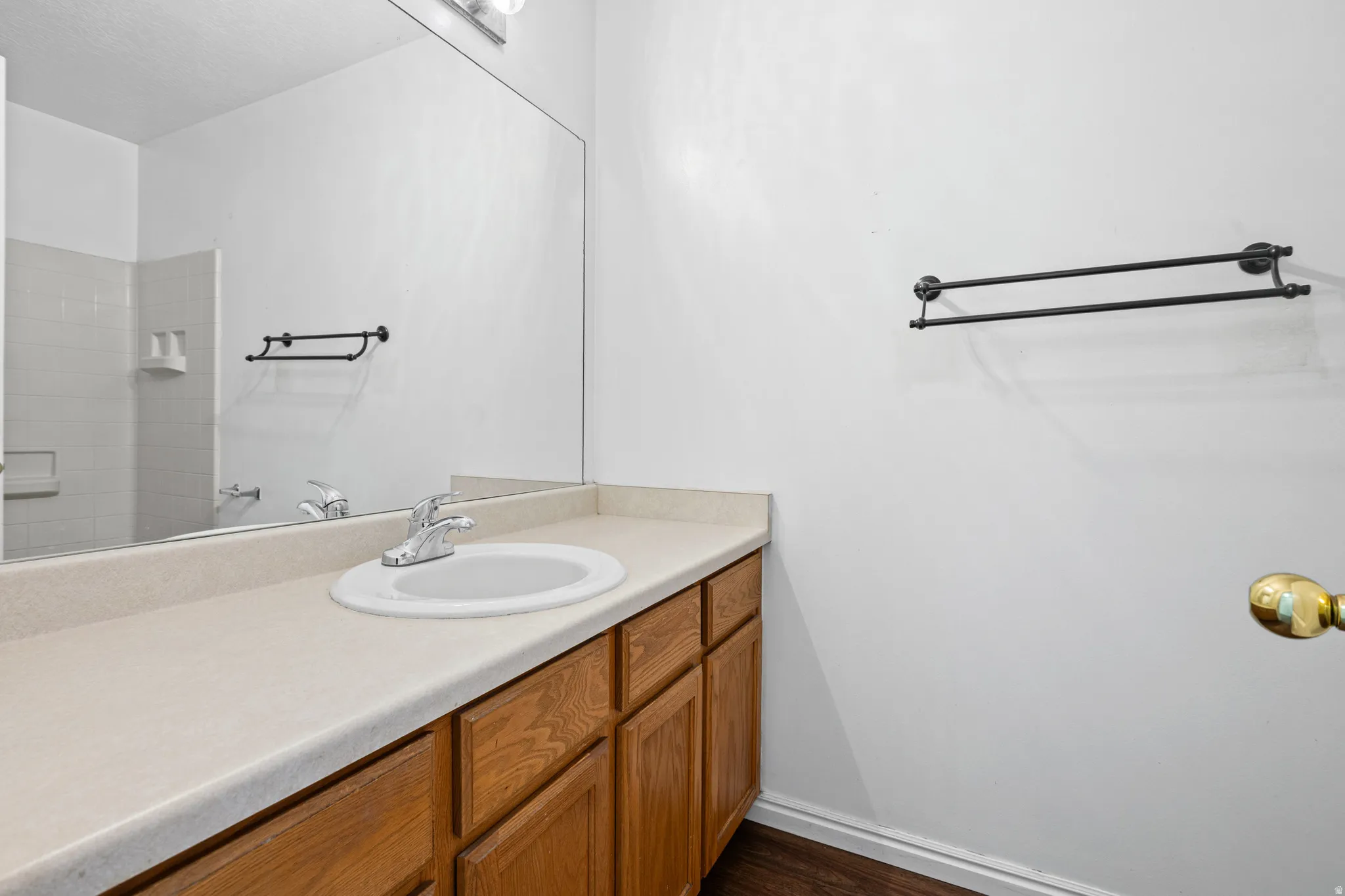 Bathroom vanity featuring a laminate countertop with an integrated sink, wood-finish cabinetry, and chrome fixtures