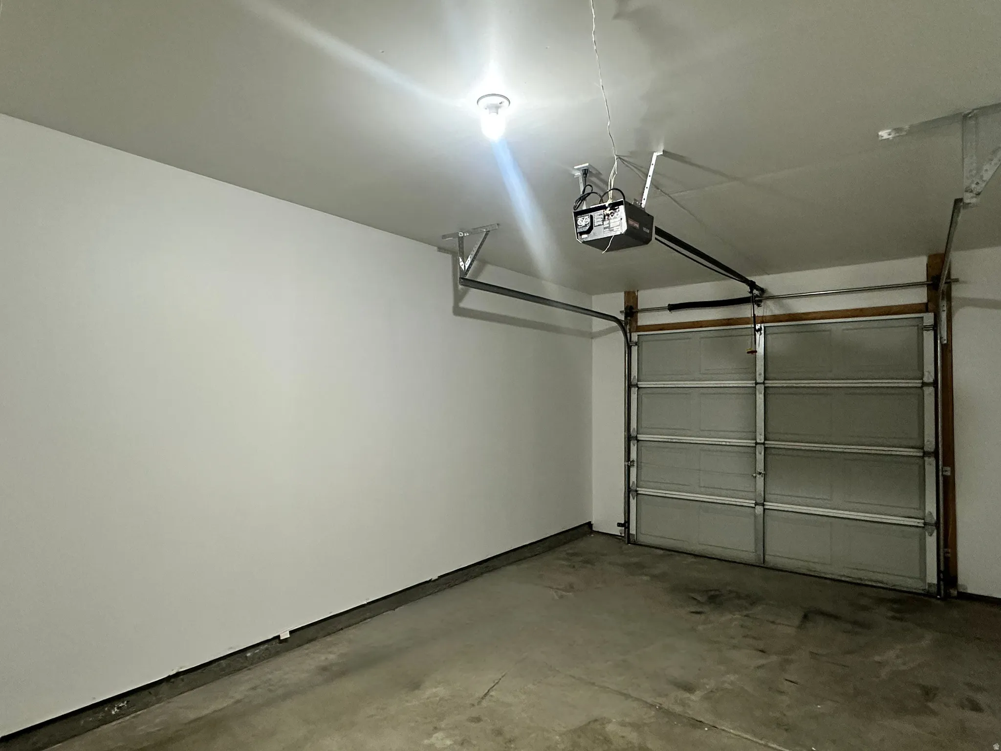 Spacious painted garage with an automatic overhead door opener and concrete flooring