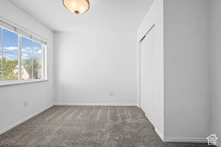 Room featuring neutral wall paint, gray carpet, a multi-pane window, and a built-in closet with sliding doors