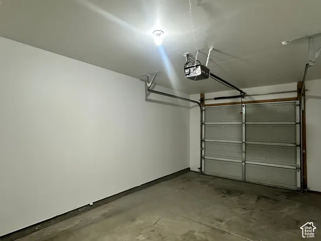Spacious painted garage with an automatic overhead door opener and concrete flooring