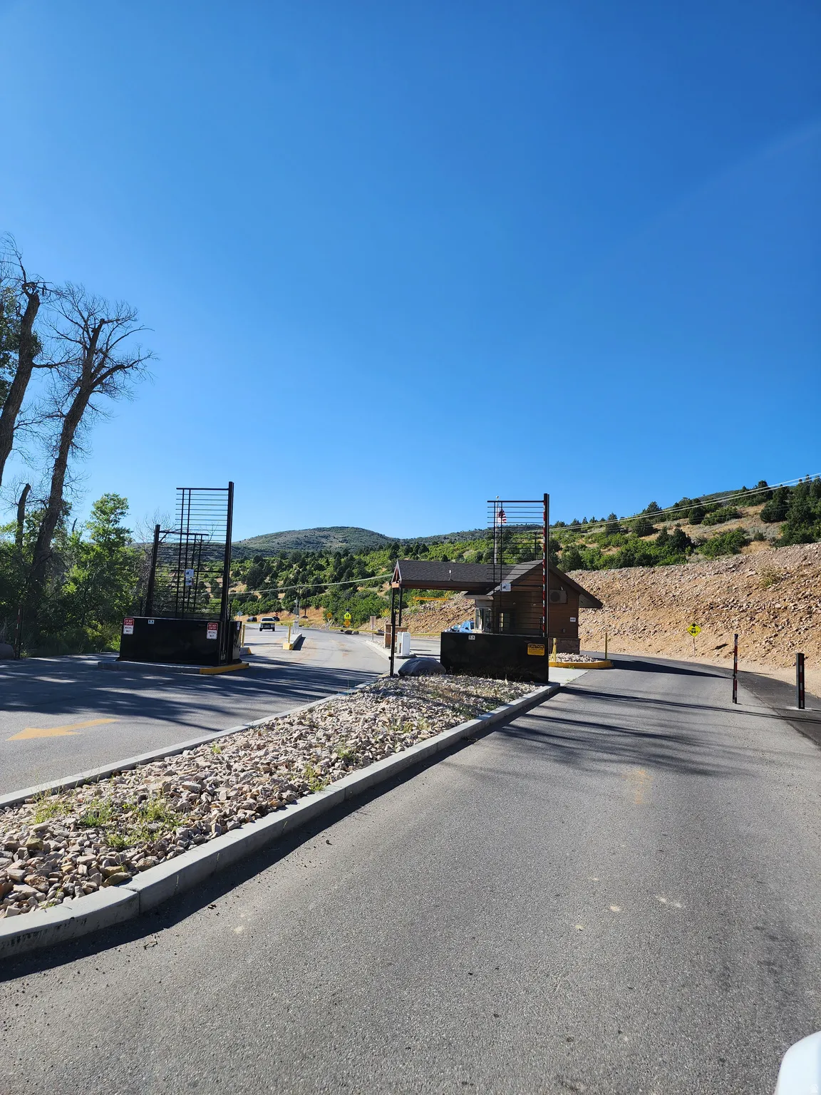 View of asphalt road featuring a gated entry, a mountain view, and curbs