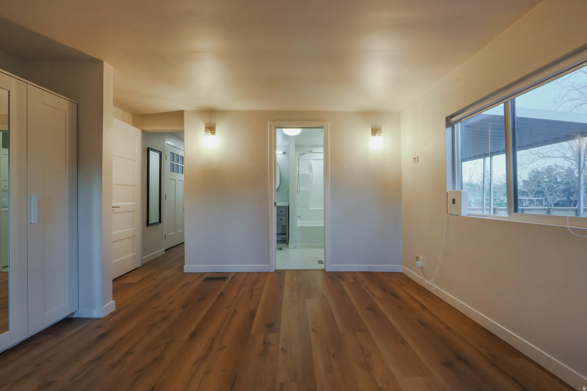 Unfurnished bedroom featuring dark wood-style floors and ensuite bath