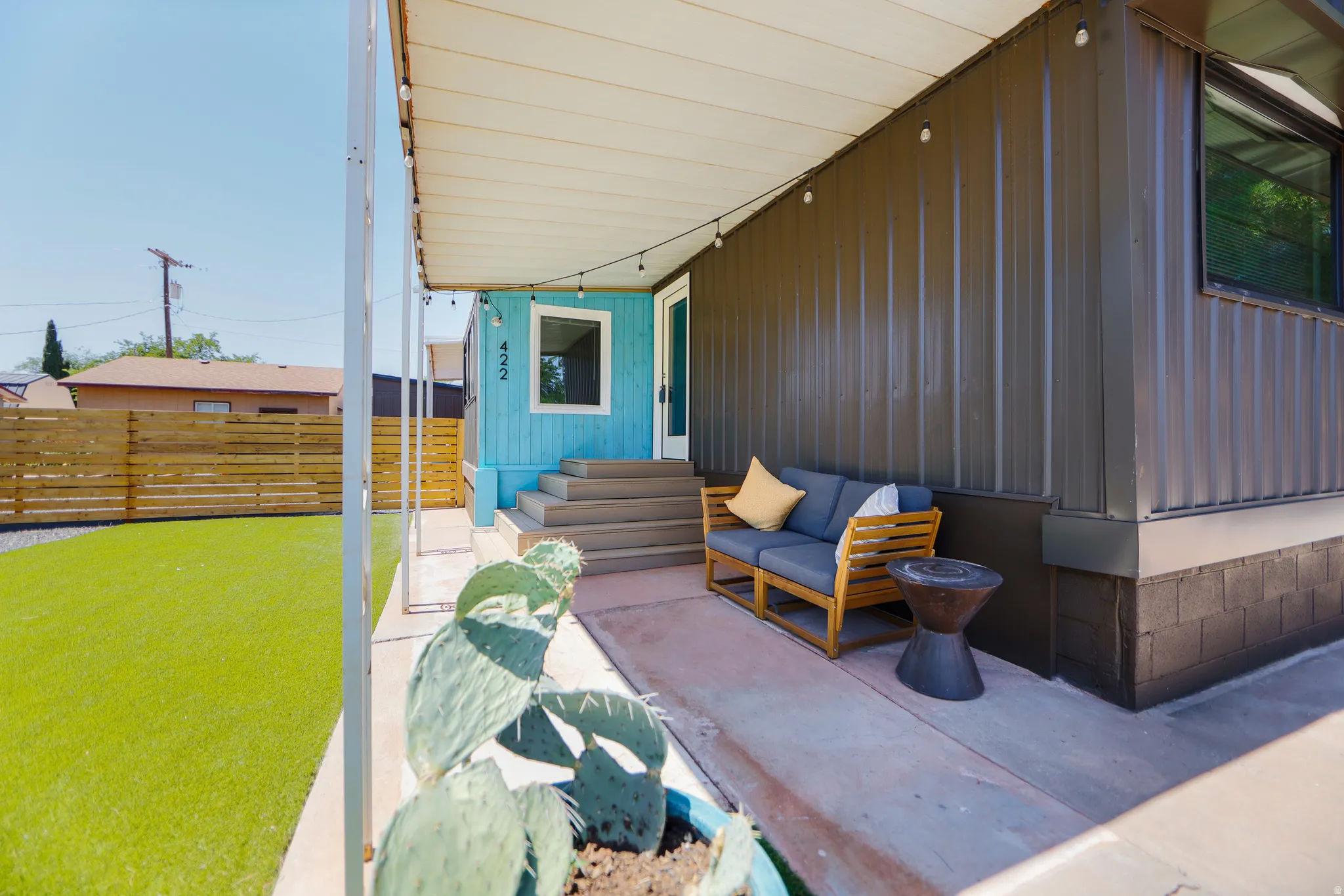 Covered patio featuring string lighting, concrete flooring, and an artificial turf yard