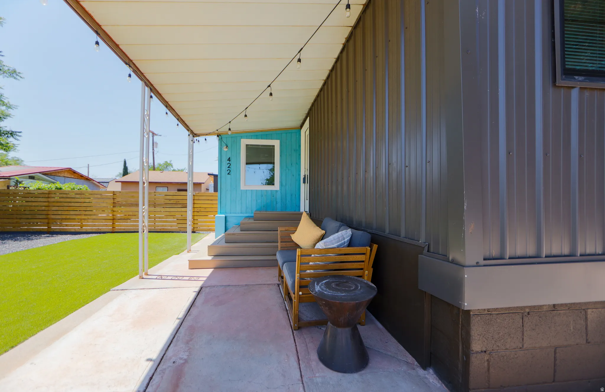 Covered porch with string lighting, concrete flooring, and metal corrugated siding