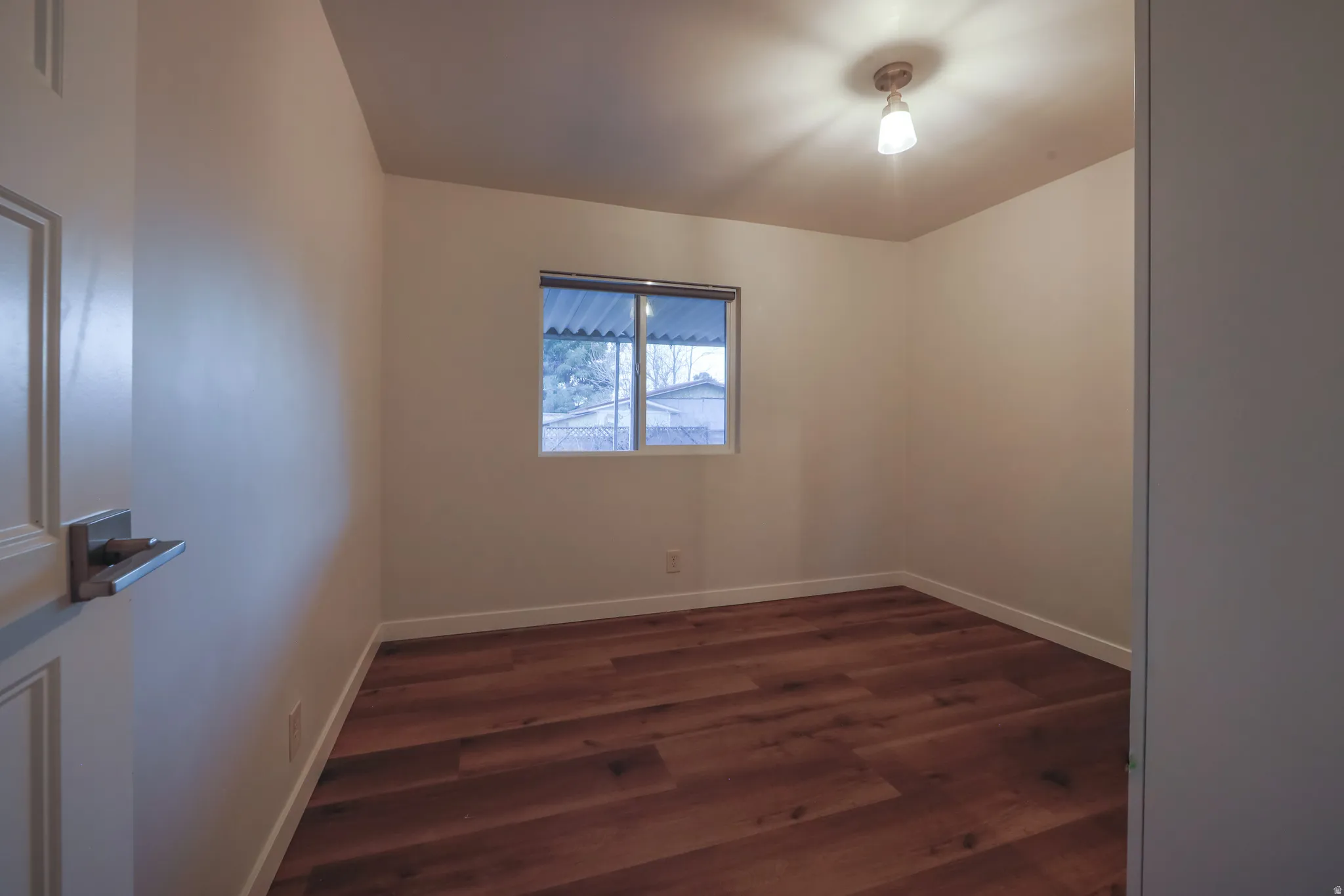 Empty room featuring dark wood finished floors and baseboards