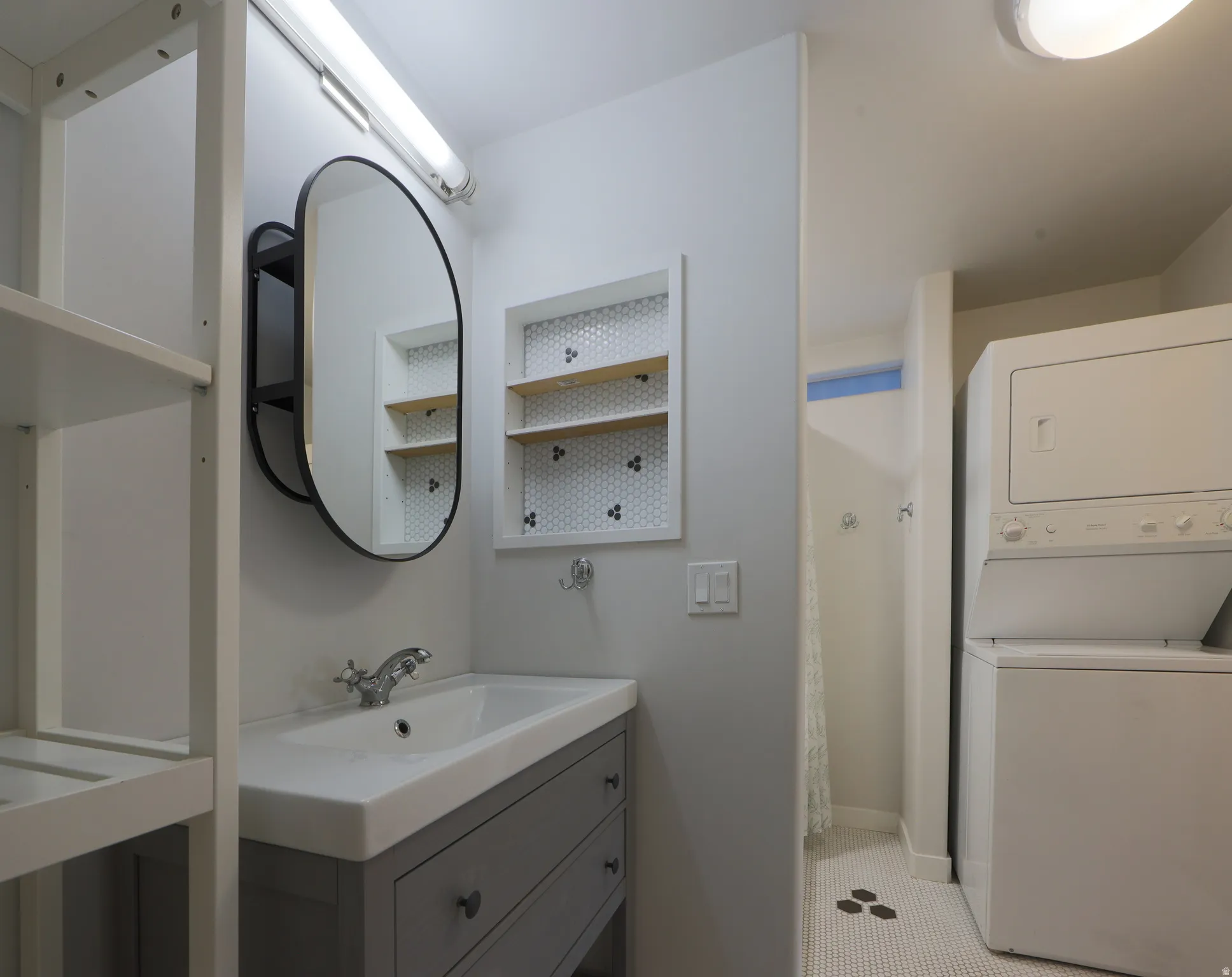 Full bathroom with stacked washer / drying machine, curtained shower, and vanity