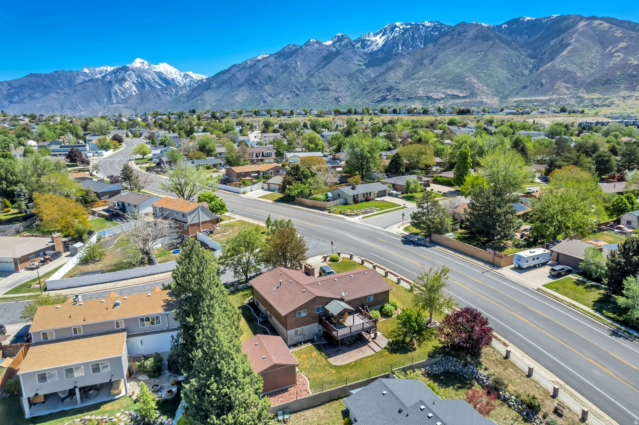 Residential property with a multi-level deck, mature landscaping, and a fenced yard