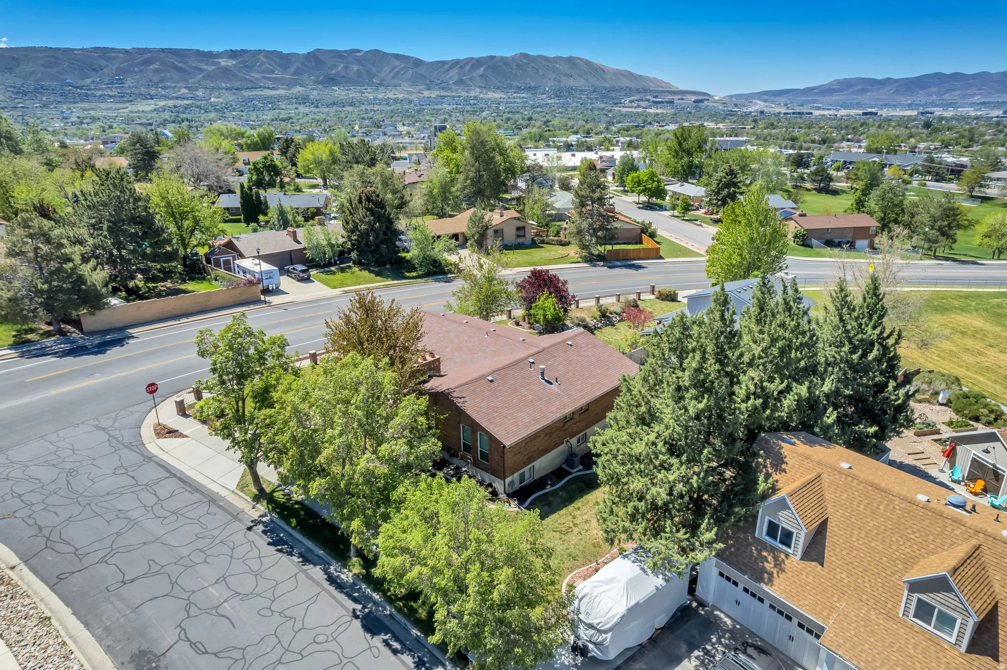 Residential property featuring a brown shingle roof, mature landscaping, and a multi-level structure