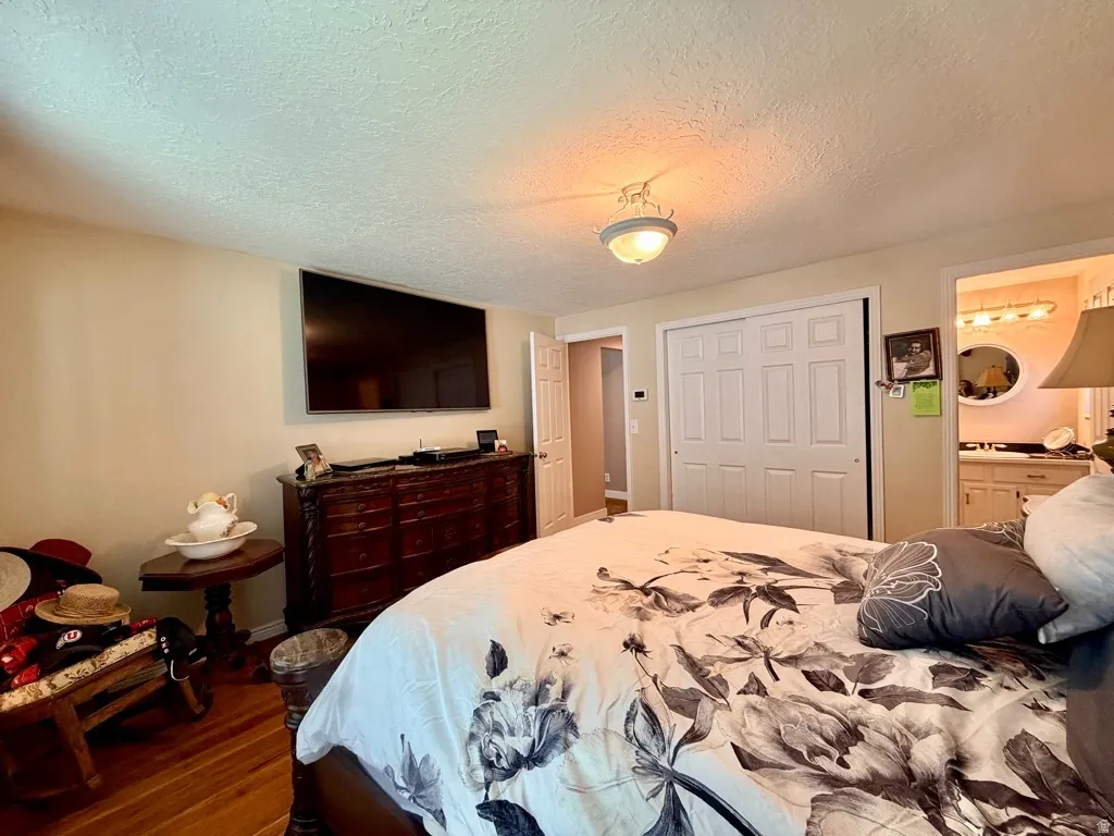 Bedroom featuring wood-finish flooring, a ceiling-mounted light fixture, and a built-in closet with bifold doors