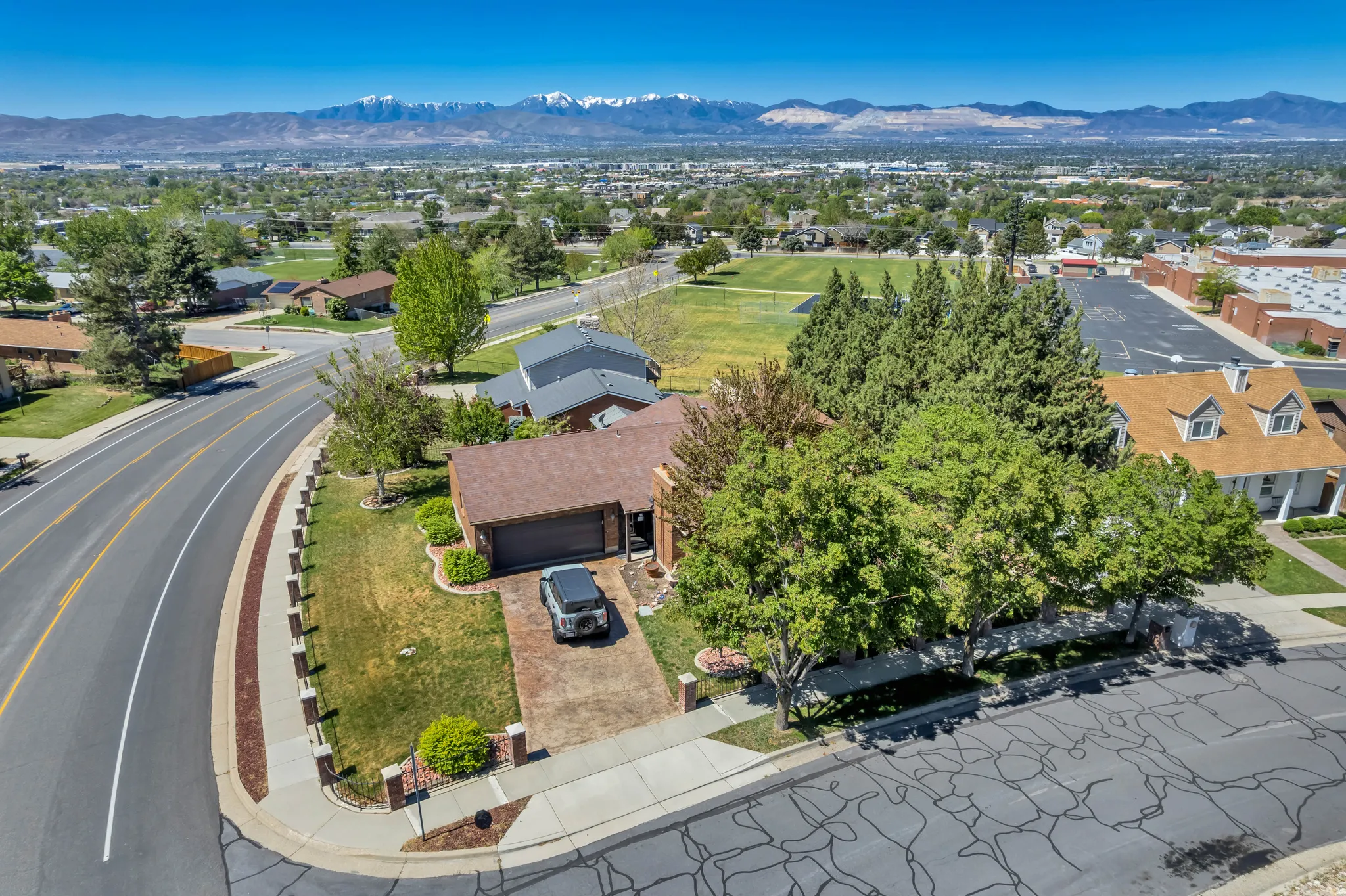 Corner lot residence featuring a brick paver driveway and mature trees