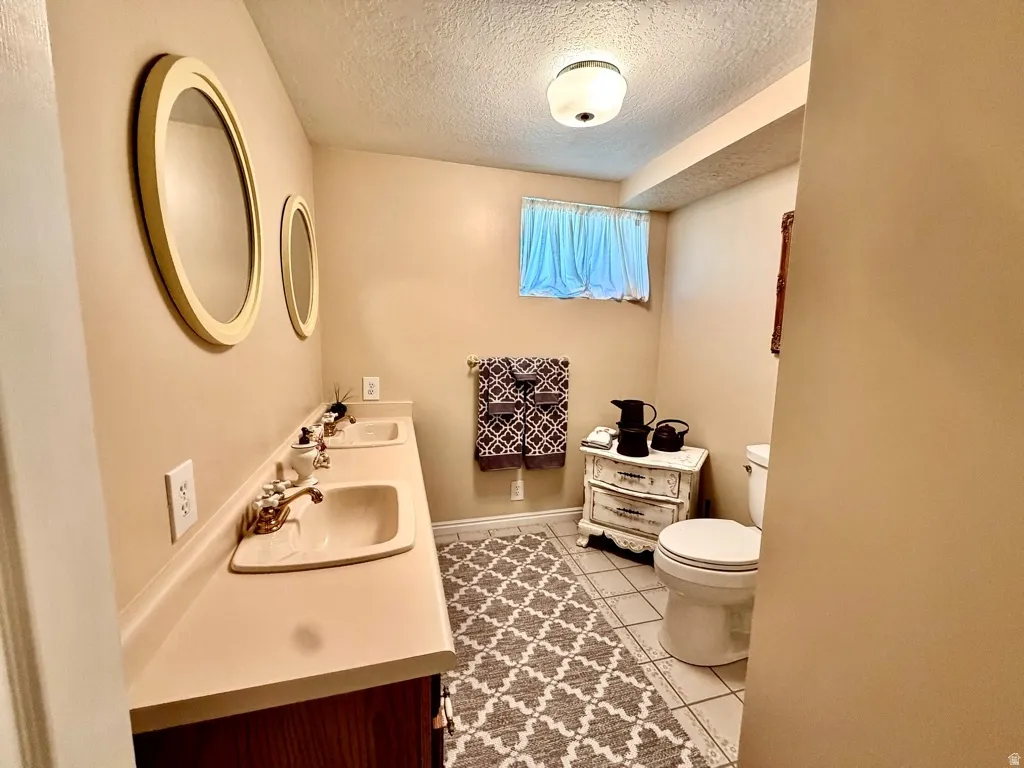 Bathroom featuring a dual vanity with integrated sinks, brass-finish faucets, and oval mirrors