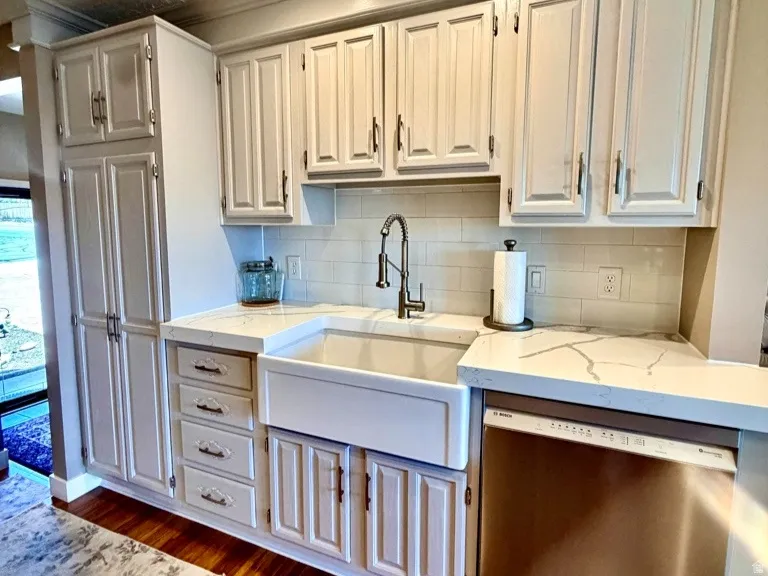 Kitchen featuring a large apron-front sink, light-toned cabinetry, stainless steel dishwasher, wood-finish flooring, and recessed lighting