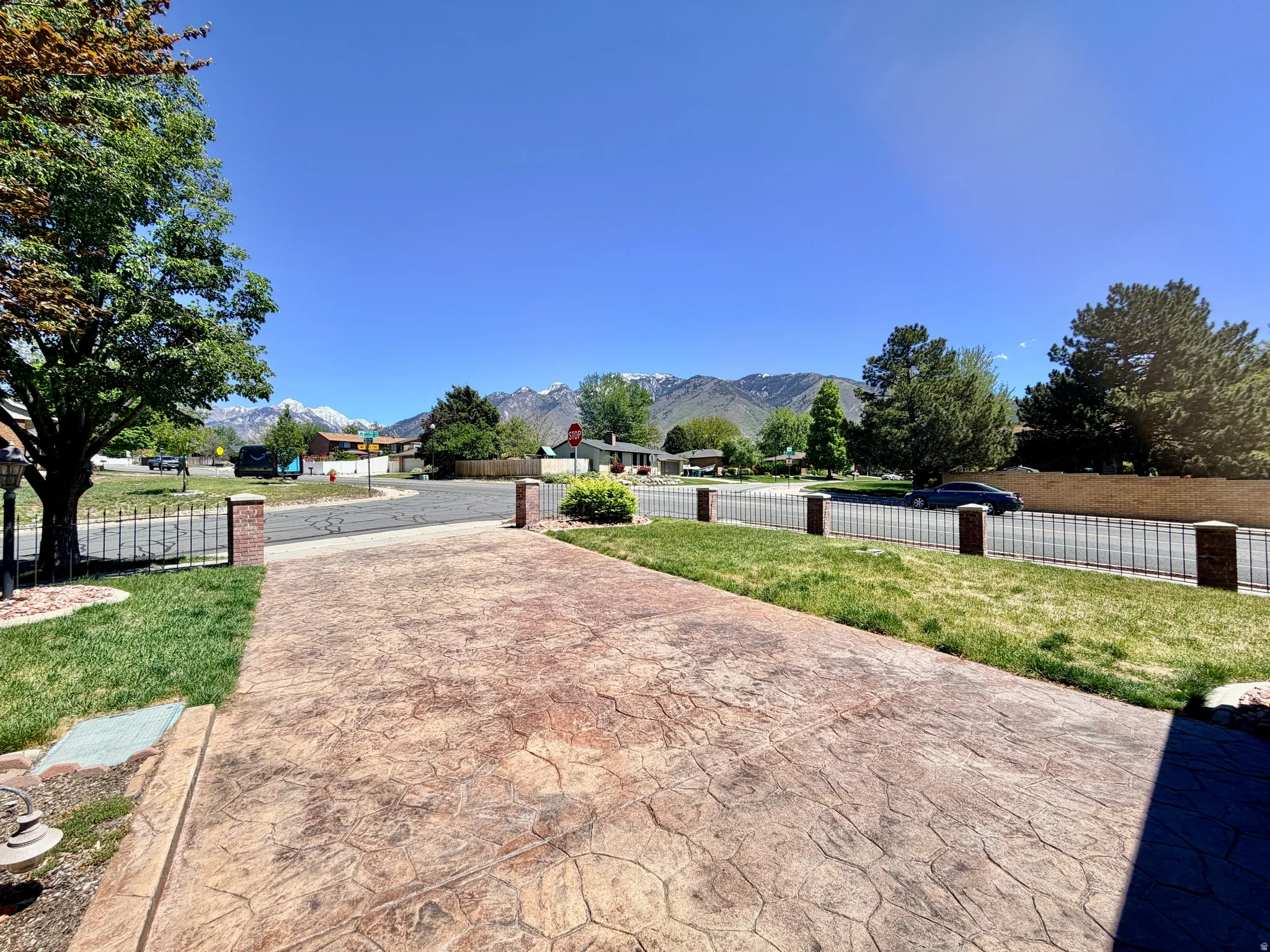 Stamped concrete driveway with a brick pillar and wrought iron fence