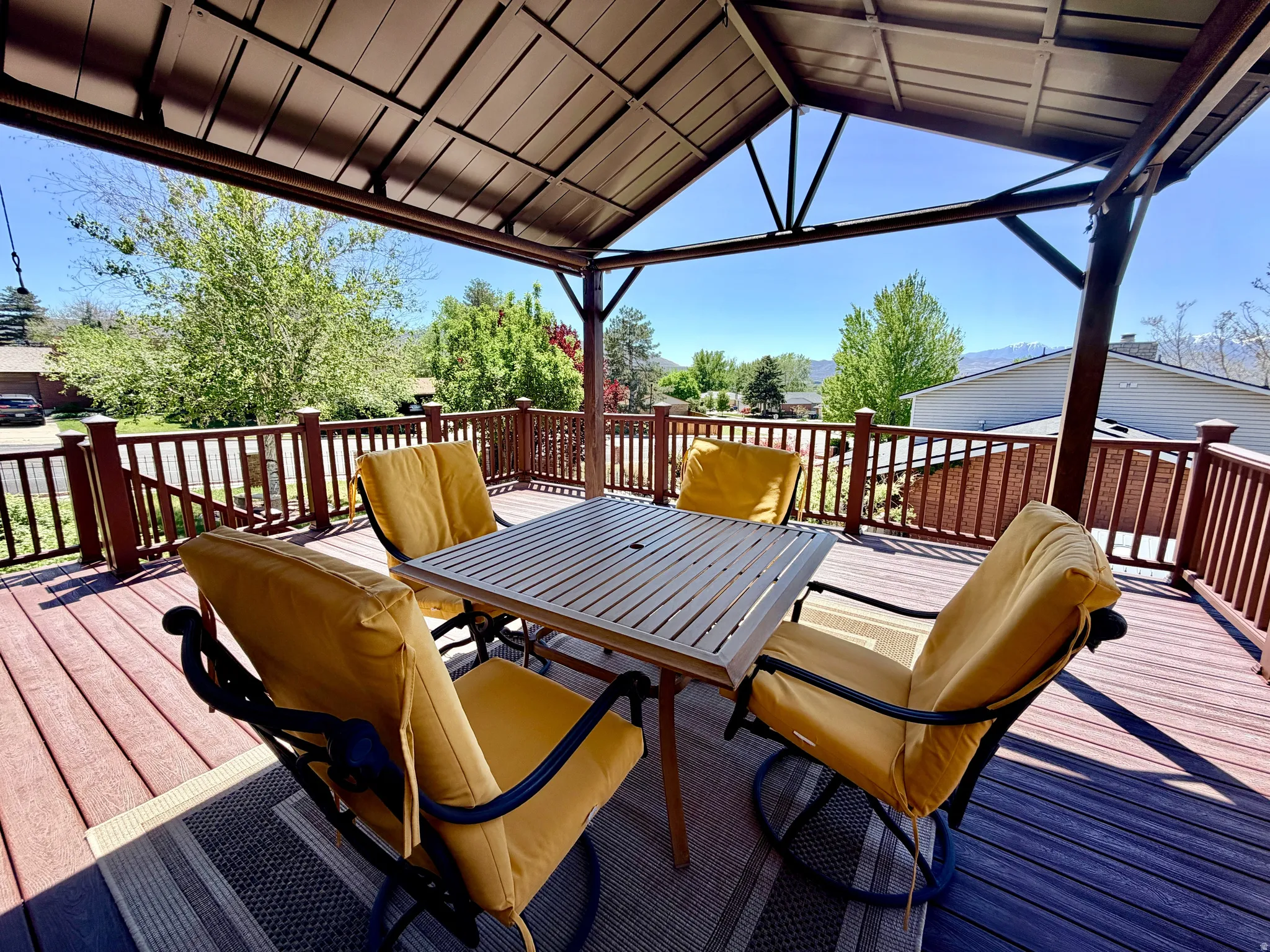 Covered outdoor deck with composite decking, brown railing, and an overhead canopy structure