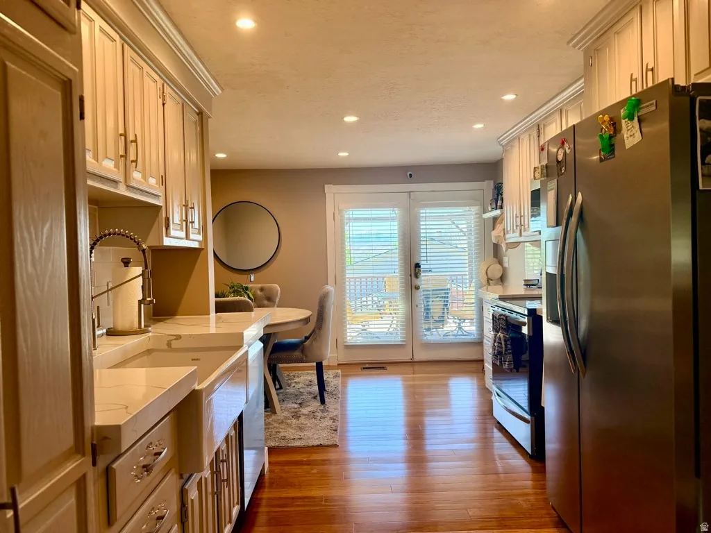 Kitchen featuring a farmhouse-style sink, stainless steel appliances, recessed lighting, wood-finish flooring, and French doors