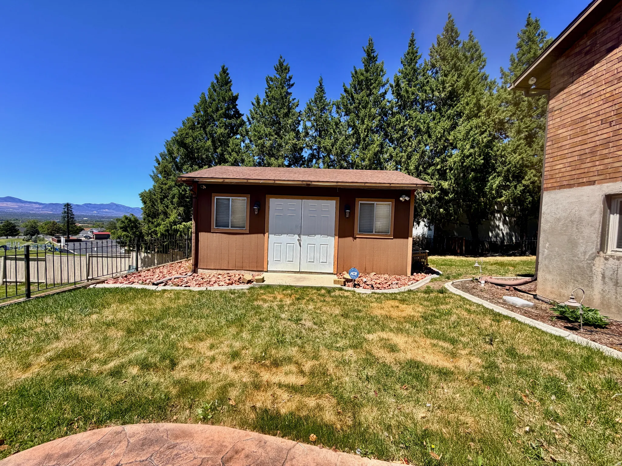 Detached brown shed featuring double white doors and a side window